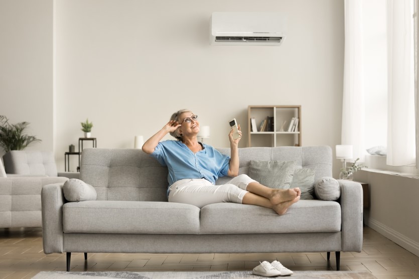 A woman sitting on a couch comfortably due to a quality HVAC system